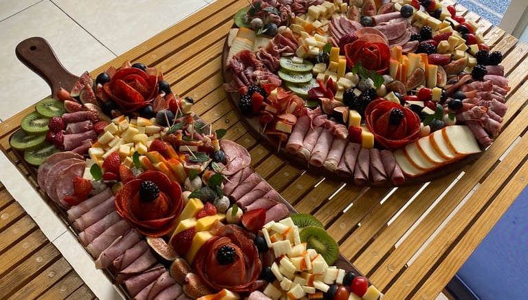 Two large charcuterie and cheese boards beautifully displayed on wooden trays.