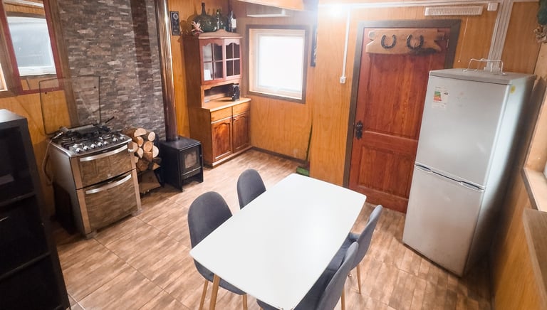 Interior de cabaña rústica equipada en Lonquimay con cocina y calefacción a leña.