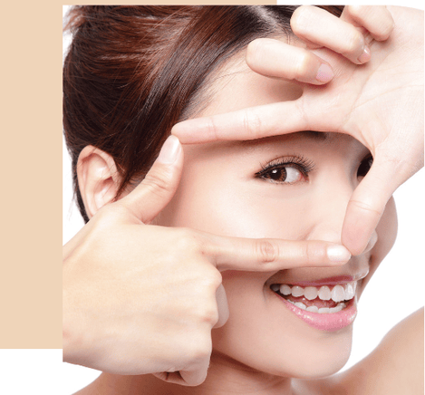 Smiling woman with clear skin and white teeth framing her face for skincare and beauty results.