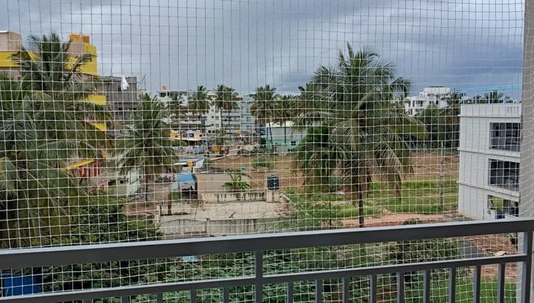 A technician carefully installing a strong monkey safety net on a residential balcony in Bengaluru.