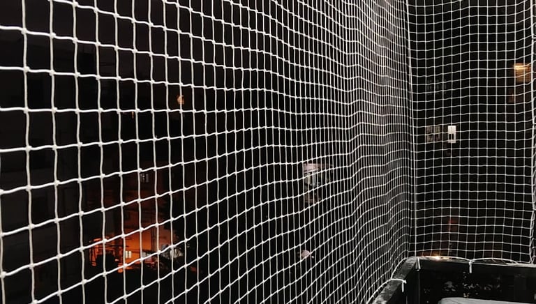 Technician inspecting and repairing a safety net on a residential balcony.