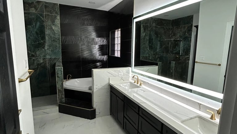 Modern luxury bathroom with double marble vanity, backlit mirror, and a soaking tub with dark tile accents.