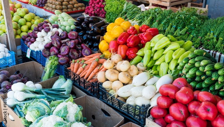 Fresh organic vegetables displayed at a farmers market, including leafy greens, carrots, and seasonal produce.