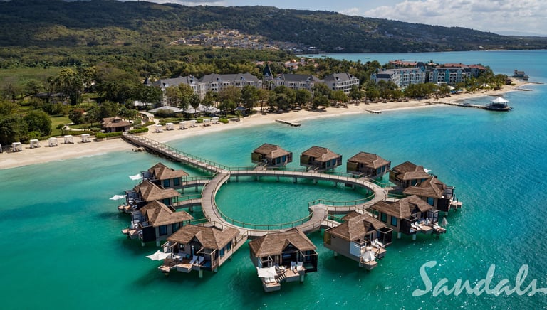 Aerial view of luxury over-the-water bungalows at a Sandals tropical Caribbean beach resort.