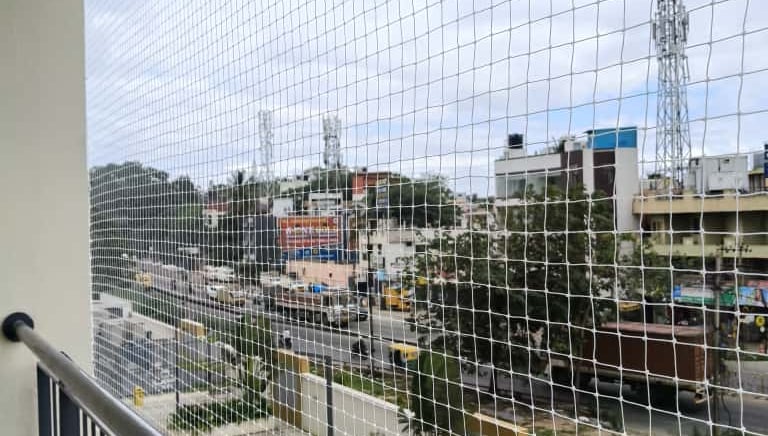 Close-up of a custom-fitted balcony safety net with a scenic city view.