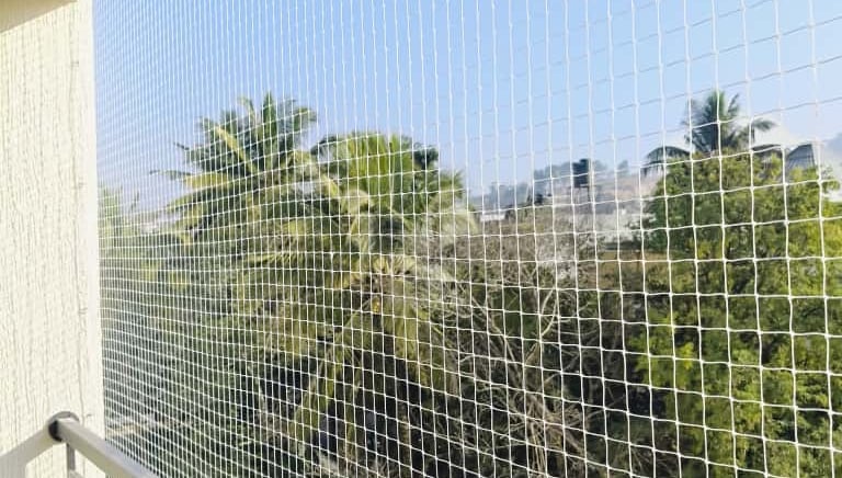 Close-up of a balcony fitted with sturdy pigeon nets against a clear sky.