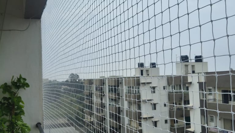 Technician carefully fitting a pigeon net on a modern balcony railing