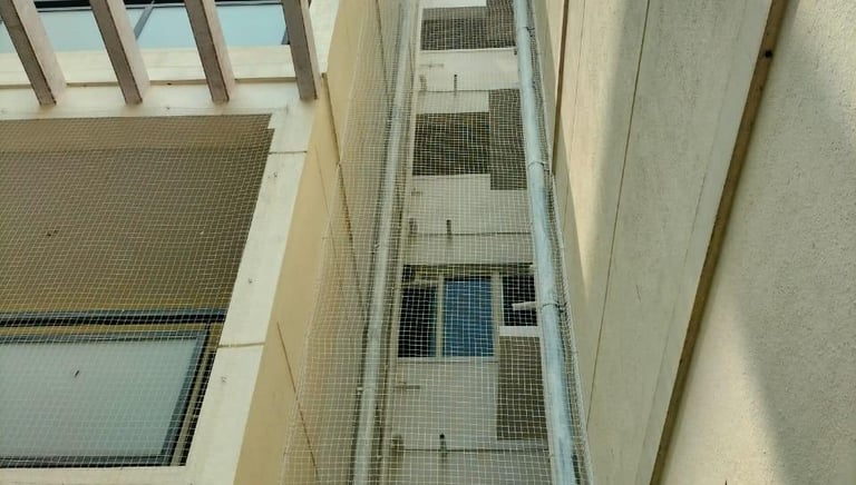 Close-up of a securely installed safety net over an apartment duct in Chennai.