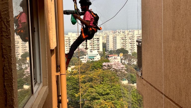 Technician installing safety net on a high-rise apartment duct.