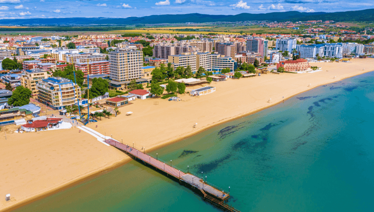 Aerial view of Sunny Beach, Bulgaria, showing a bustling sandy beach, turquoise Black Sea, and a pier extending into the