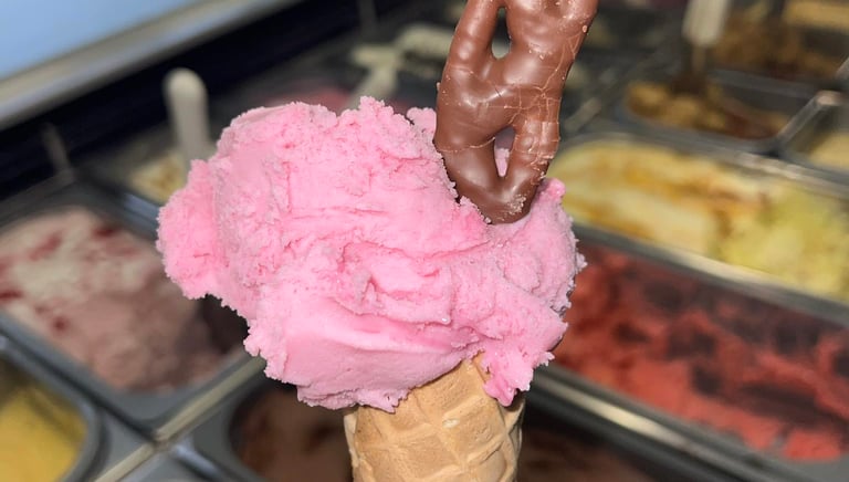 Single scoop in cone. Strawberry flavour with Curly Wurly. Ice cream display.