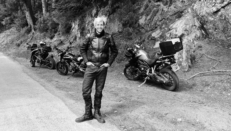 Dan next to three motorcycles parked up at the side of the road near a rocky area