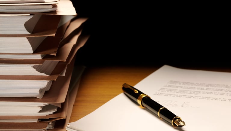 Elegant pen resting neatly beside neatly stacked files representing archival quality formatting.