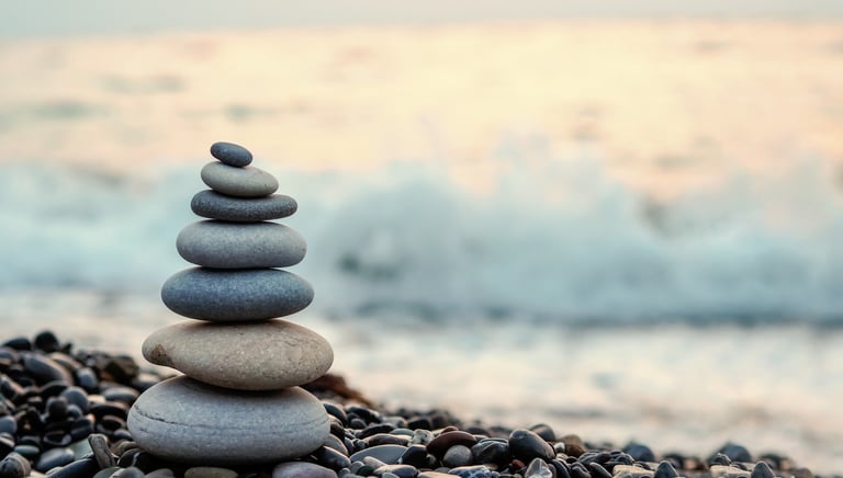 Stacked stones balanced near the ocean symbolizing peace and preparation before loss.