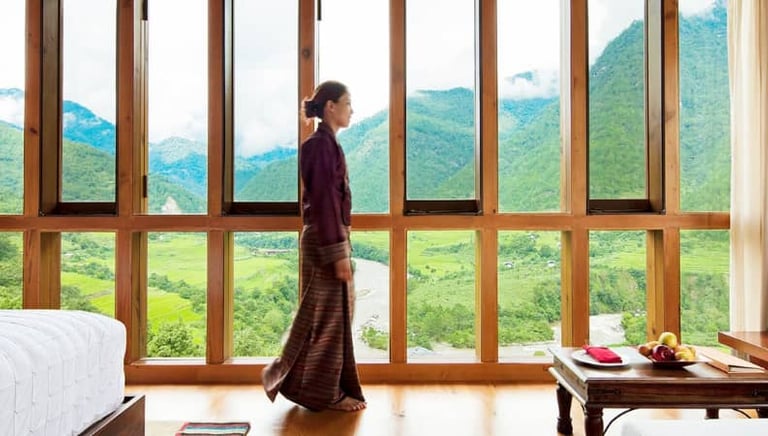 a Bhutanese woman standing in front of a large window at Como Uma Hotel in Punakha, Bhutan.