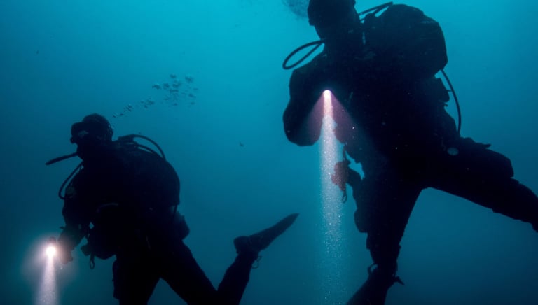 two divers in the water with a flashlight