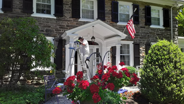 a painter on a ladder painting the front of a house