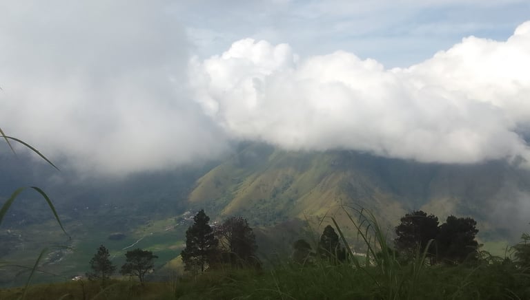 On a mountain top overlooking a valley with clouds hiding the peaks of other mountains