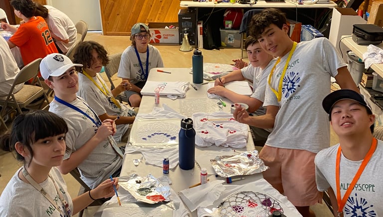 a group of people sitting at a table with paint