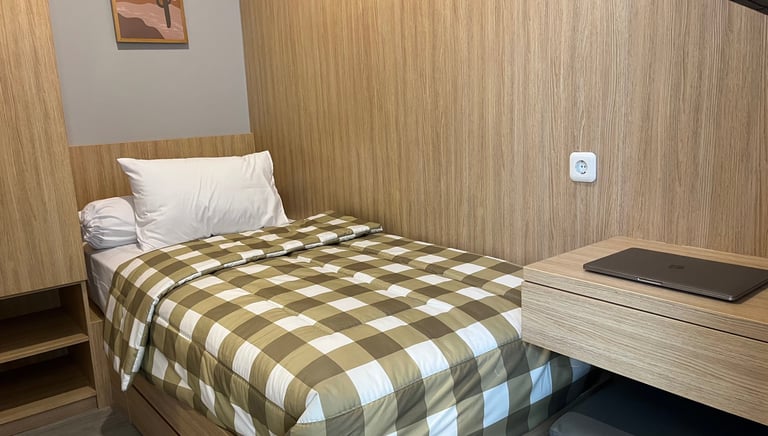 Kamar kos eksklusif Kos Si Bos Surabaya dengan single bed, meja belajar, lemari kayu, dan suasana modern minimalis