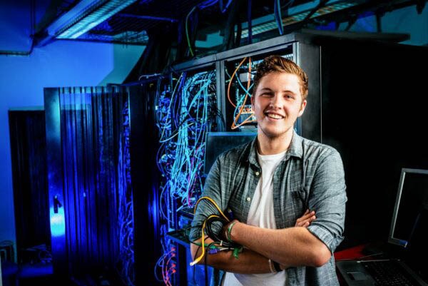 a man in a server room with a laptop and a laptop