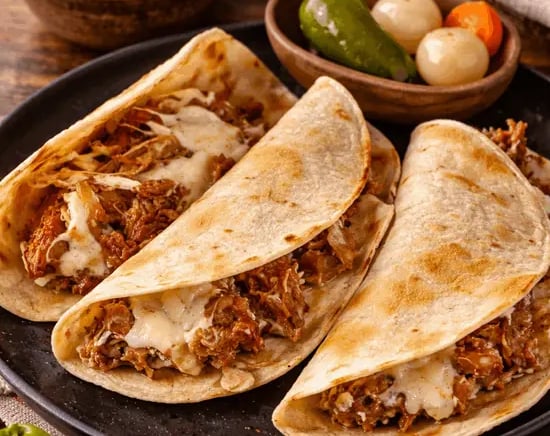 Quesadillas de barbacoa de res con queso fundido, salsa y limones en Querétaro.