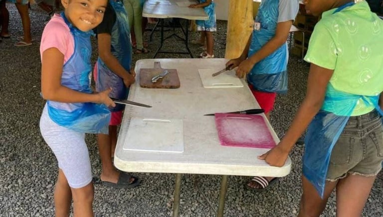 a group of children are standing around a table for crafts