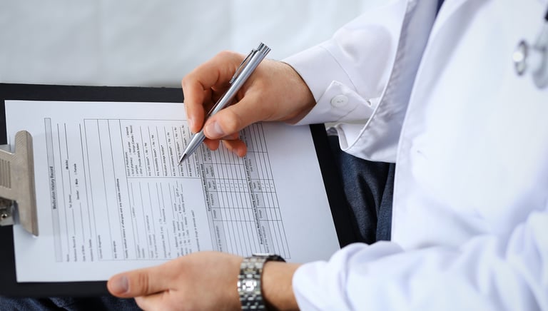 Profesional de salud llenando un formulario de evaluación médica ocupacional en una carpeta.