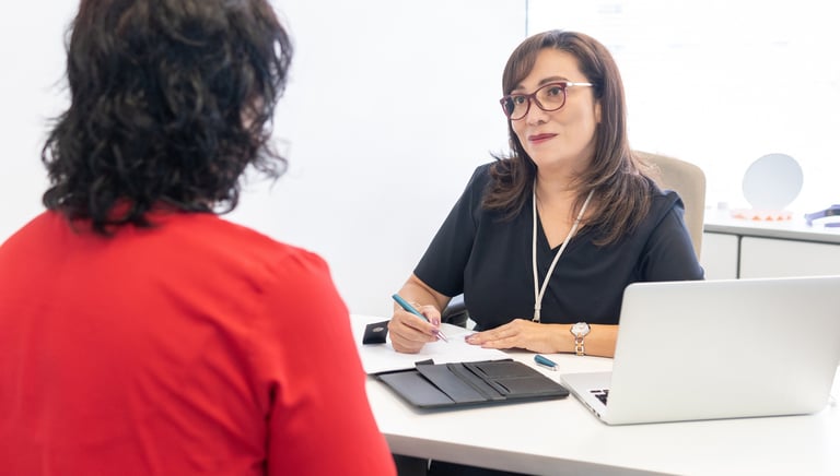 Asesora brindando orientación personalizada a un cliente sobre normativas STPS en una oficina