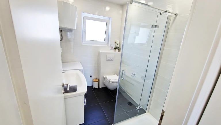 bathroom with a shower, sink and washing machine 