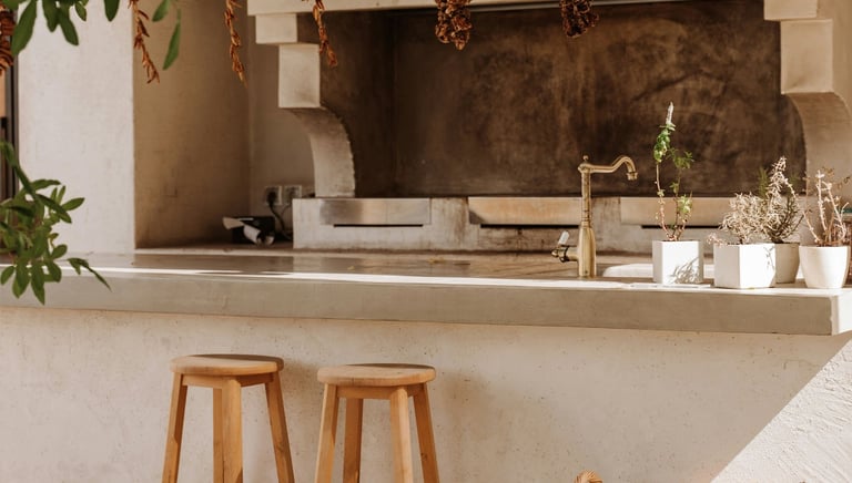 Zona exterior de un bar con taburetes de madera, grill y barbacoa