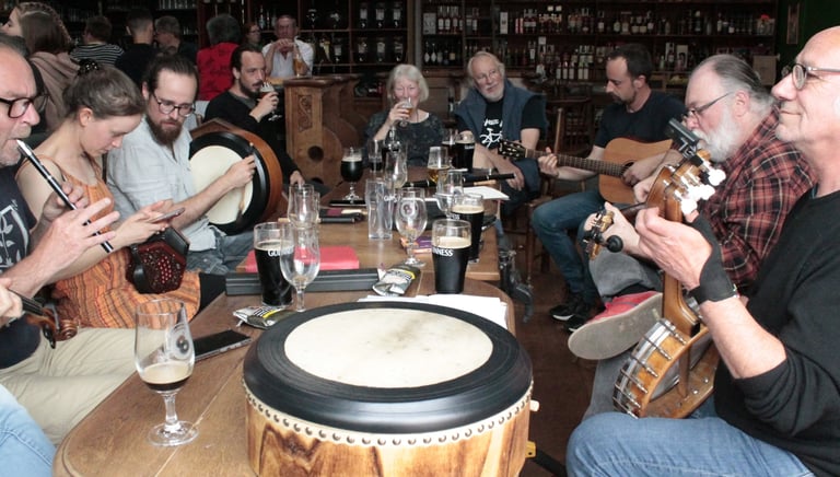 Musicians playing traditional Irish instruments and drinking Guinness during a live pub session.