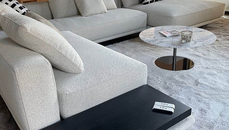 Canapé d’angle gris clair moderne avec table basse en marbre dans un intérieur de salon luxueux.