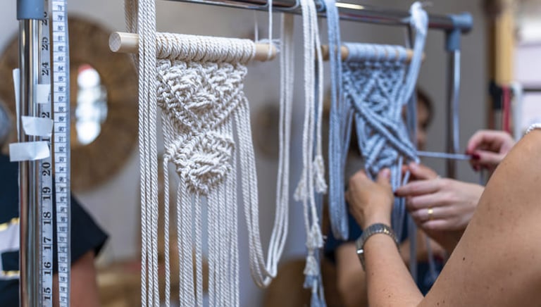 Proyectos de tapices de macramé hechos a mano colgados en un soporte metálico.