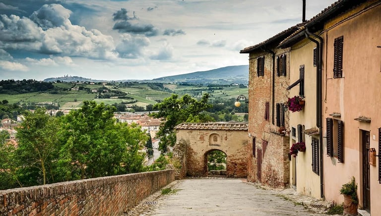 Cobblestone street in medieval Certaldo Alto, Tuscany, featuring historic architecture and panoramic valley views