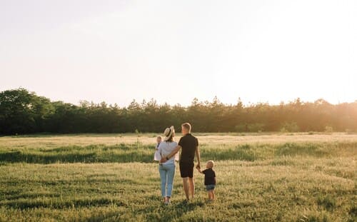 familia joven caminando en una pradera al atardecer