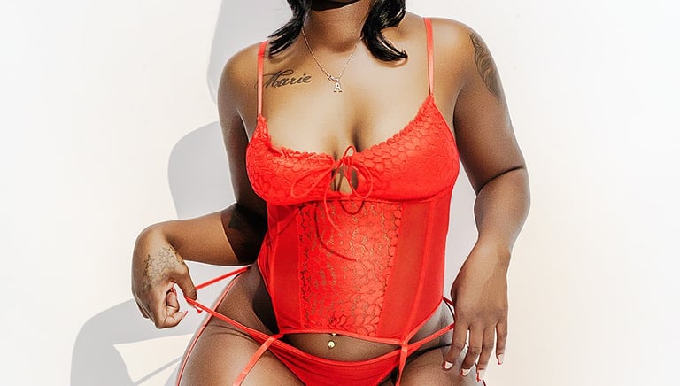 a boudoir model woman in a red lingersuit posing for a photo
