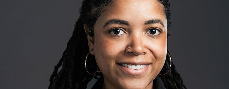 headshot of a woman with long hair and earrings on her head