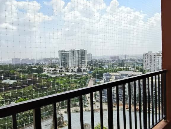 A close-up of a securely installed pigeon net on a residential balcony with sunlight filtering throu