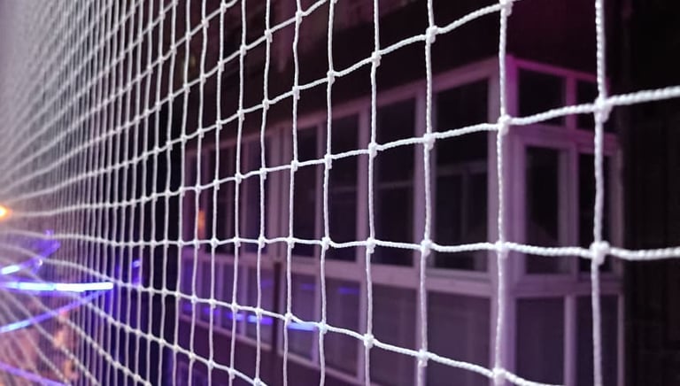 Close-up of a tightly woven safety net securely fastened to a balcony railing.