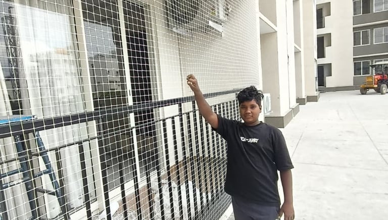 Technician carefully installing a pigeon net on a high-rise balcony in Mumbai.