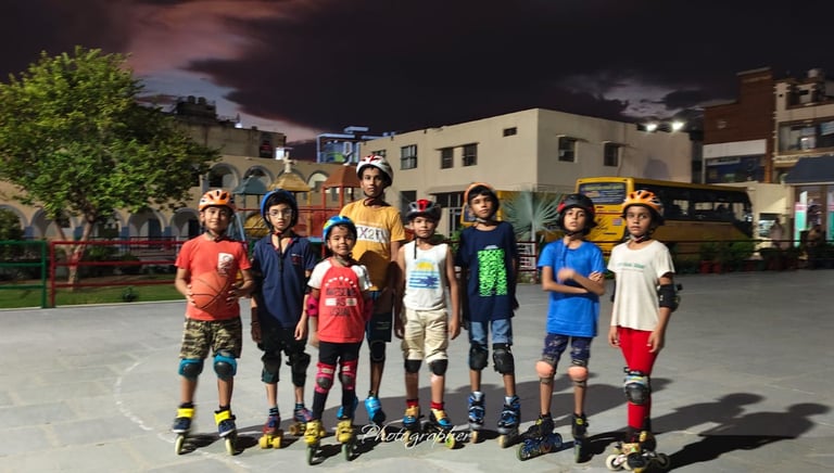 A group of young children wearing helmets and safety gear posing with roller skates on an outdoor rink at night.