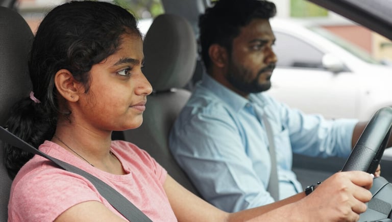 Smiling instructor guiding a learner driver inside a car on a sunny day.