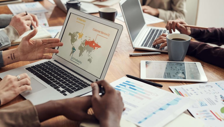eam reviewing business analytics charts on laptops and printed reports