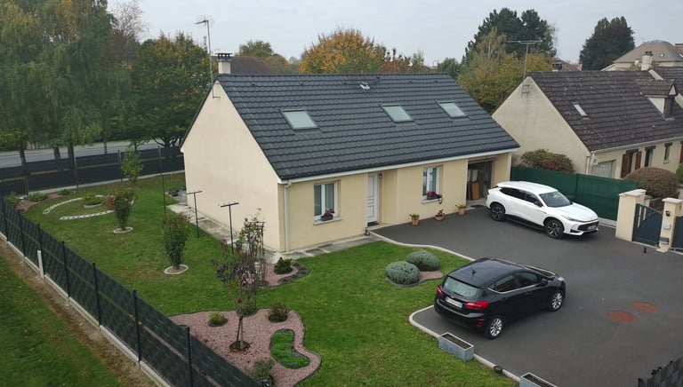 Maison moderne avec un toit en tuiles sombres, des puits de lumière et un jardin paysager
