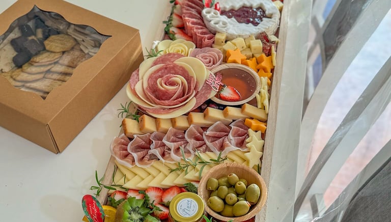 abla de charcutería navideña festiva con rosas de salami, brie, aceitunas y fruta fresca.