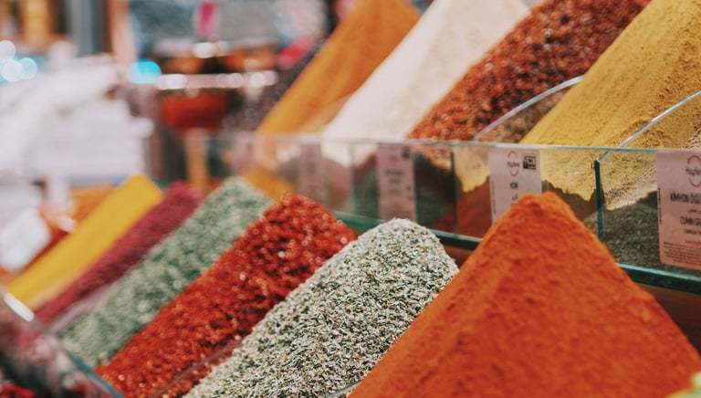 Colorful display of various spice powders in a Turkish spice market, featuring turmeric, chili powde