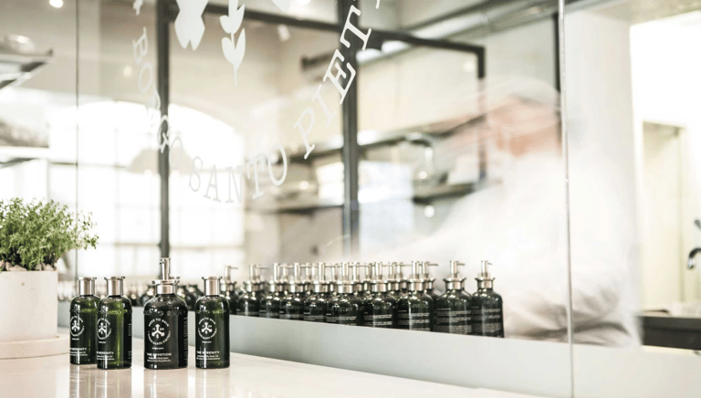 The Alche’Mist Serum Spray bottle beside green micro-algae and water droplets