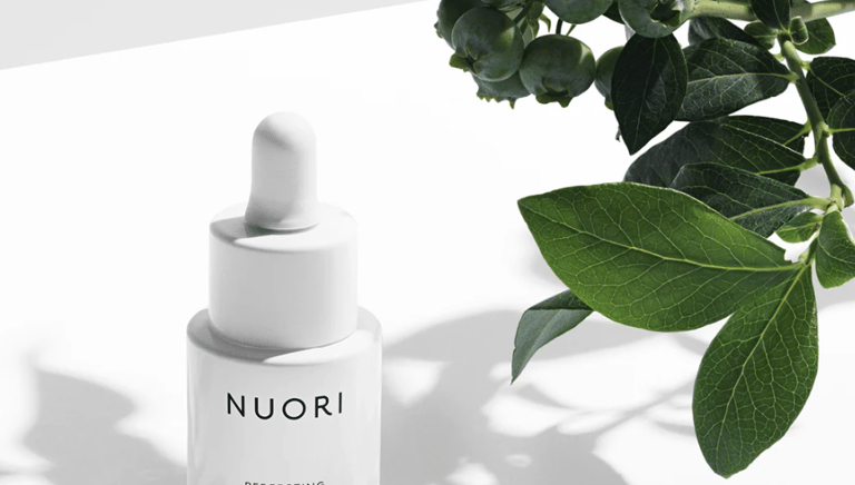 Minimalist NUORI skincare bottles arranged on a white marble surface