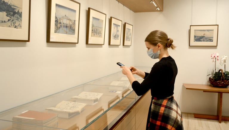 Madison looking at illustrated books by Hokusai in the vitrine